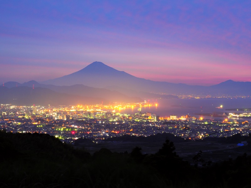 富士山と港と夜景が写せる有名なスポット。かすみの中に浮かぶ富士山が美しいと感じ、シャッターを切った。標準域で眼下の街並みを取り込むような構図を作った。<br><span class="fnt-85">OLYMPUS OM-D E-M1 Mark II / M.ZUIKO DIGITAL ED 12-100mm F4.0 IS PRO / 29mm（58mm相当） / マニュアル露出（F7.1、25秒） / ISO 200</span>
