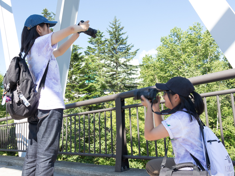 白ひげの滝近くの橋の上で撮影する選手