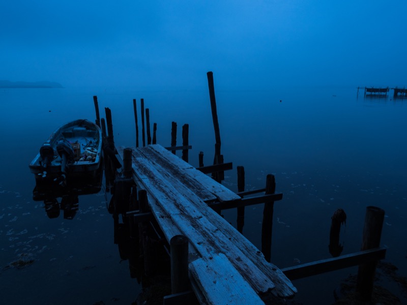 霧が濃い夜明け前の湖畔。かなり暗い中でも手持ち撮影で快適に撮れるため、これまで三脚が必須なために撮ることができなかったさまざまなアングルから撮ることができた。<br><span class="fnt-85">OLYMPUS OM-D E-M1 Mark II / M.ZUIKO DIGITAL 12-40mm F2.8 PRO / 12mm（24mm相当） / 絞り優先AE （F5.6、0.8秒、-0.7EV） / ISO 200</span>