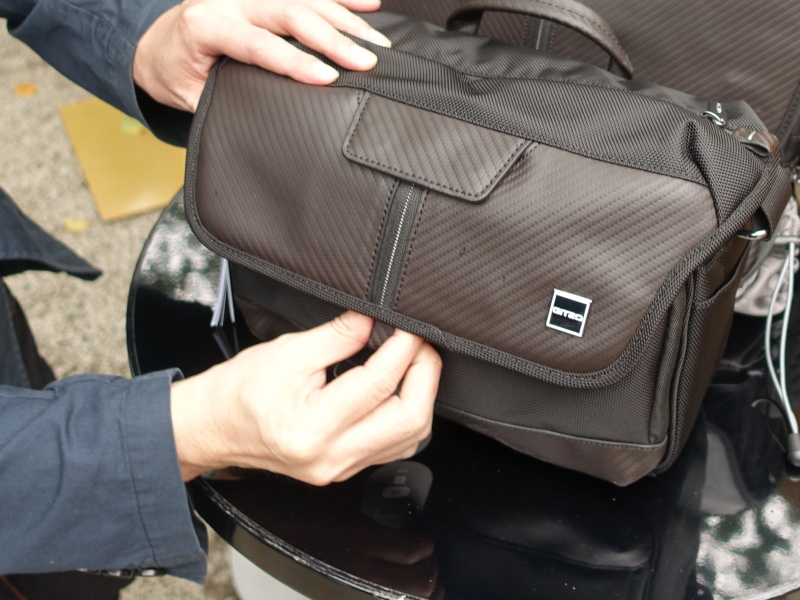 フラップ下部のタブを下方向に引っ張るとロックが開き、フラップを閉じる際は操作なしでロックされる機構。フラップ上部には、磁石ロック式のレンズキャップ収納部