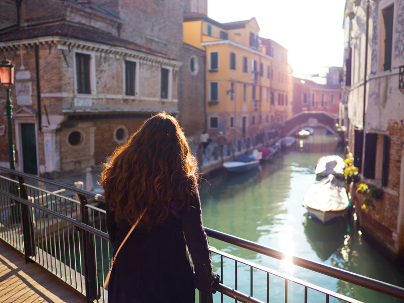 朝の低い光線が建物の間から運河を抜けて乱反射し、橋の上で佇む少女のカーリーヘアーが柔らかな逆光で際立っていた。輝く髪の毛は繊細に解像されている。<br><span class="fnt-85">OLIMPUS OM-D E-M1 Mark II / M.ZUIKO DIGITAL ED 17mm F1.2 PRO / 17mm（34mm相当） / 絞り優先AE（F1.2、1/6,000秒、-0.5EV） / ISO 200</span>