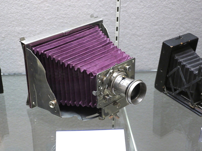 ドイツ・H.マダーの完全金属製フォールディングカメラ「インビンシベル」（1898年）。クロームメッキに赤蛇腹の外観が特徴的。130×180mm乾板。