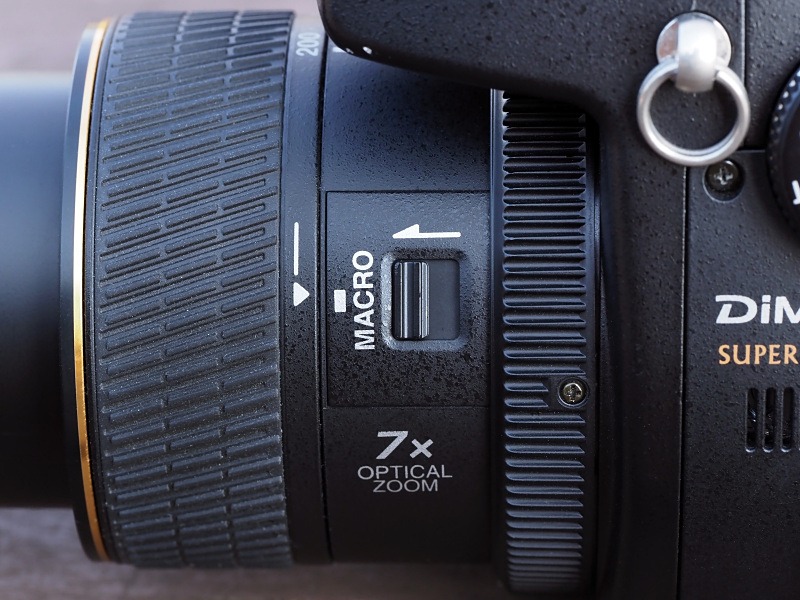 レンズ鏡筒の側面に配置される「マクロ切り替えレバー」。マクロに切り替えると、望遠側だと多少ズームできる。だが、広角側は広角端に固定される。