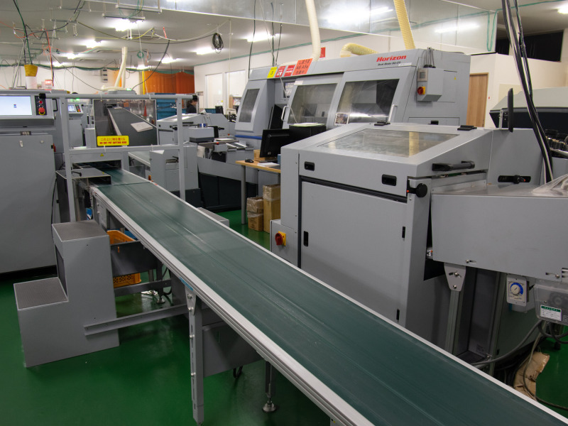 生産設備の間にはベルトコンベアを増設し、可能な限り人の手を介さずに生産が行なえる体制を整えている。