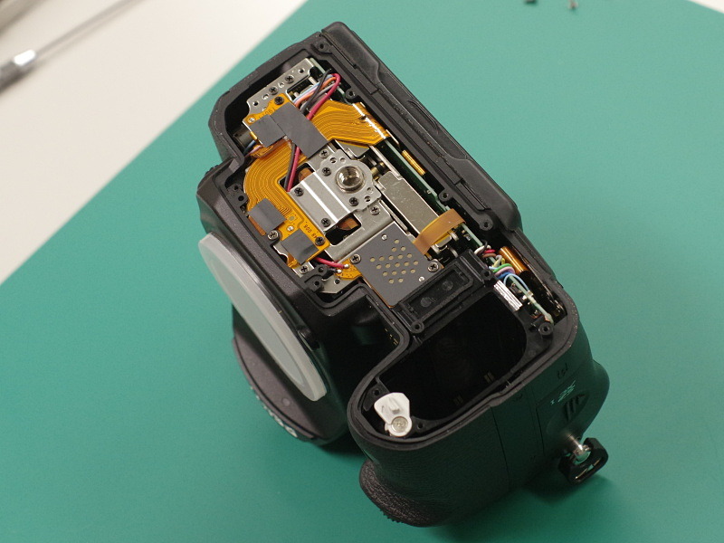 背面液晶モニターや各操作部から伸びるフレキシブルケーブルのコネクターを外し、メイン基板交換の準備が完了。右上は、交換用の基板。