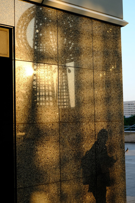 撮影者名：チャット<br>作品についてのコメント：「GOLDEN WALL」　夕日が壁に反射して、オブジェの影とともにGOLDに輝いている様が美しかったので撮影しました。それだけではつまらないので、ちょっとお疲れの通行人もいれました。