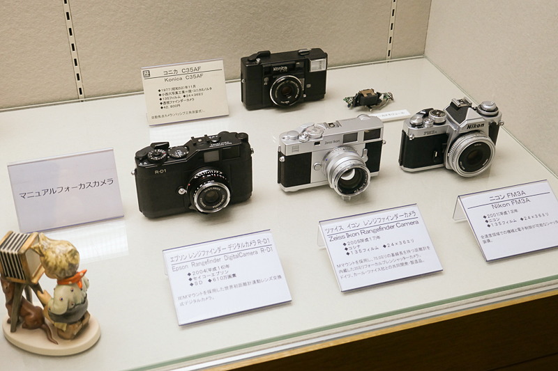 「ピントの魔法」より、様々なマニュアルフォーカスカメラ。一番後ろは、オートフォーカスを広めた歴史的カメラ"ジャスピンコニカ"。