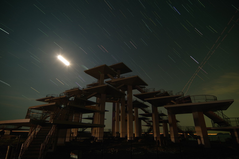 南西方向を向いて撮影。星は左上から右下へと動いている。明るく太い輝線は沈みゆく月の光。