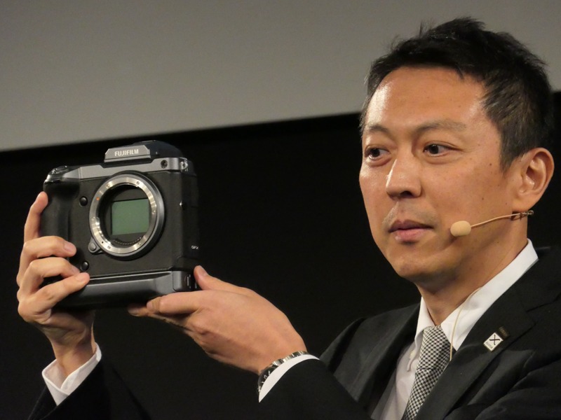 開発発表の「GFX 100 MEGAPIXELS」を手にする飯田年久氏。