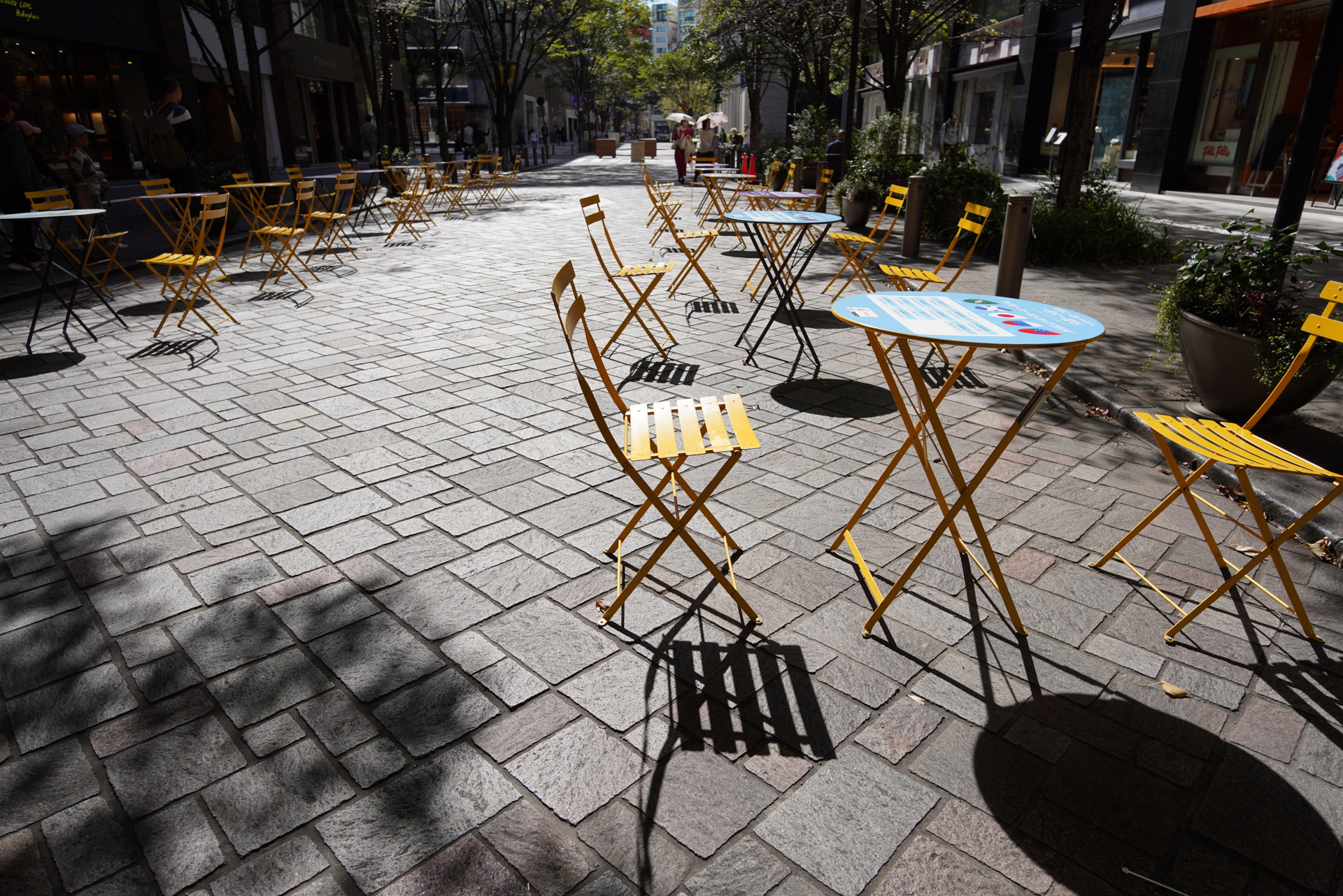 丸の内通りは、平日と休日で時間帯は違うが365日間歩行者天国になる。テーブルが置かれて街角カフェのようになった雰囲気を狙った。陰影を強調するために逆光で、広さを加えるために腰ぐらいの高さから撮影した。α7R III / ISO 100 / F5.6 /  1/500秒