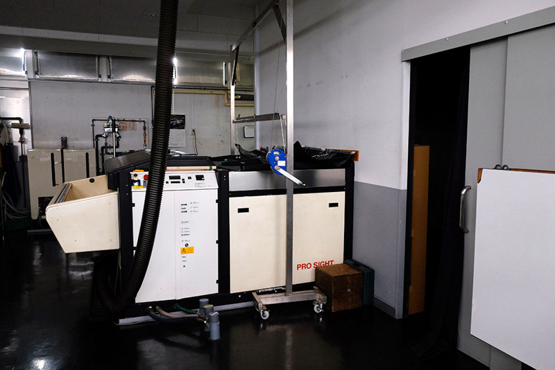 暗室でセットされたロールは、壁を隔てた外の現像処理機へ。