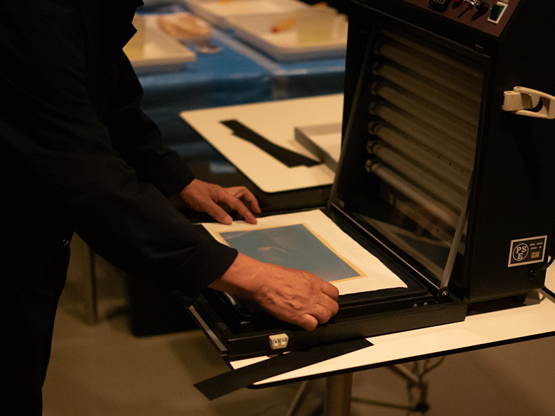 印画紙とデジネガを紫外線露光機にセット。ガラスで押さえたあと、バキューム機構で平坦性を確保する。