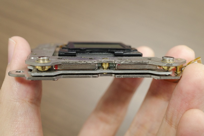 写真上下のフレームに挟まれた中央の板部分にセンサーが載り、これがボイスコイルモーターで平行移動することにより手ブレを補正する。