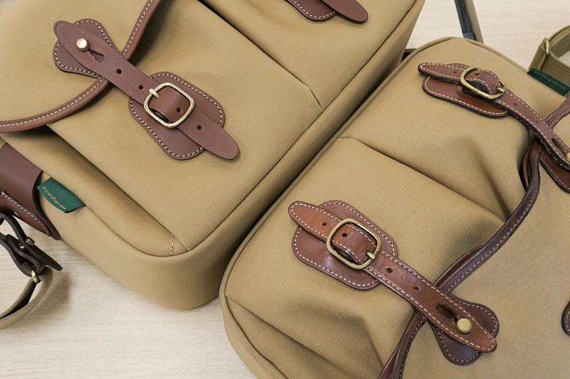 右は筆者私物のハドレープロ。革らしく使用感が出てきた。ベルト部分に袋の持ち手を通して両手を空けたり、いろいろ無理の利く構造がお気に入り。