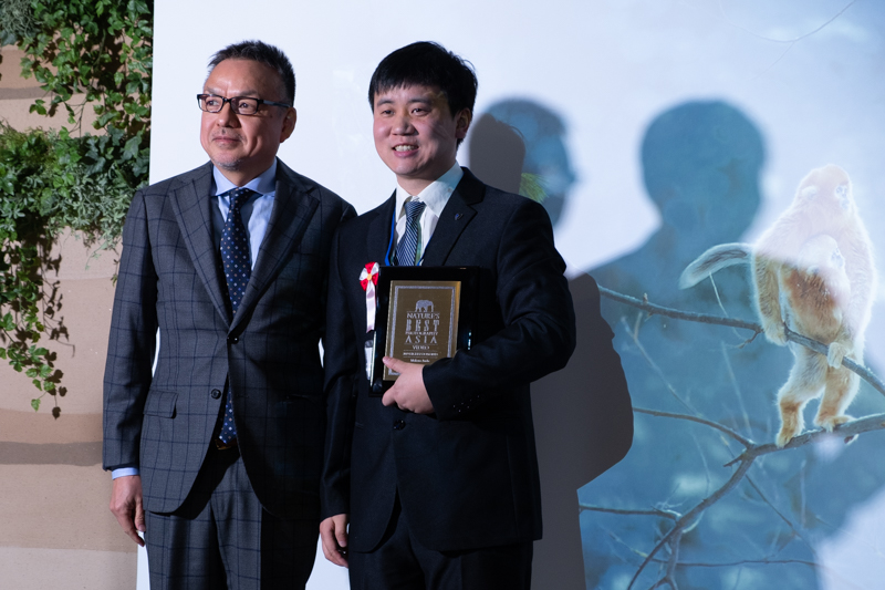 Qiang Zhang氏（右）。ネイチャーズベストフォトグラフィーアジアの代表理事を務める伊藤光氏（左）より楯が授与された