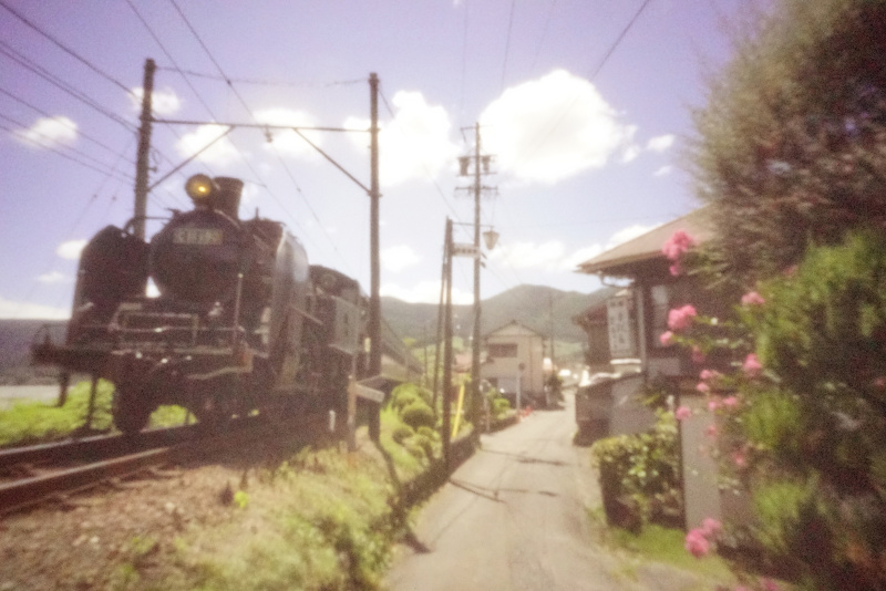 「おもひでかめら」のゆるくてやさしい描写力は、古い被写体とベストマッチ。とくに蒸気機関車を撮影すると、まるでタイムスリップしたかのような写真になります。SLだけでなく、懐かしい街並を入れることで、SLのある日常風景を演出してみました。<br>ソニーα7S II　マニュアル露出（1/160秒）　ISO 64000　WB:日陰（A+2）　ニュートラル