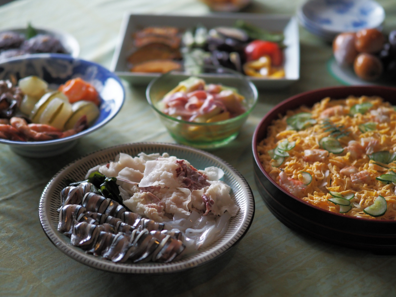 ピントが合っている皿はキビナゴとクジラの刺身。普段の食卓にクジラが並ぶところが長崎らしい。最短撮影距離が50cmの本レンズはテーブルフォトにも最適（撮影：斎藤巧一郎）。<br><span class="fnt-85">OLYMPUS OM-D E-M5 Mark III / M.ZUIKO DIGITAL ED 45mm F1.2 PRO / 45mm（90mm相当） / 絞り優先AE（F1.2、1/50秒、-0.3EV） / ISO 800 / WB：オート</span>