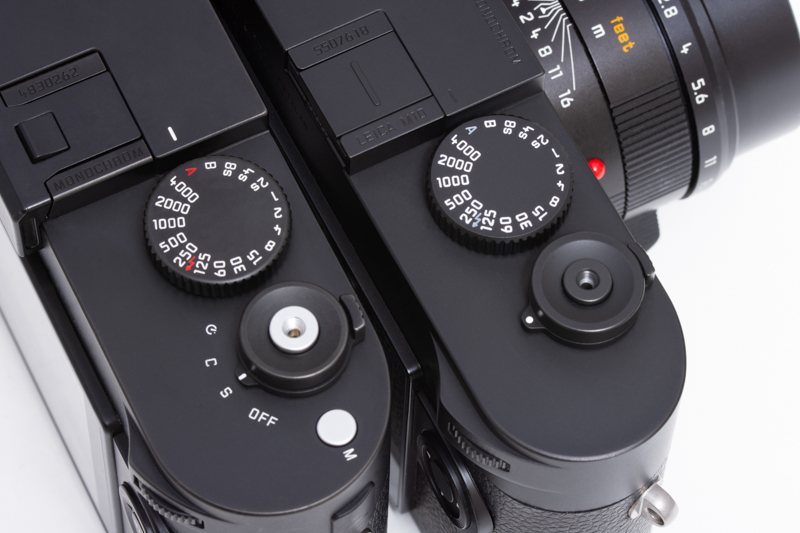 前方がライカM10モノクローム。後方のTyp246はシャッターボタンがシルバーだがライカM10モノクロームはブラック。シャッターダイヤルのAやシンクロ速度のマークも赤に対してグレーだ。またライカM10モノクロームは動画機能がないため動画（M）ボタンがない。電源スイッチ周りも文字はなくシンプルだ。