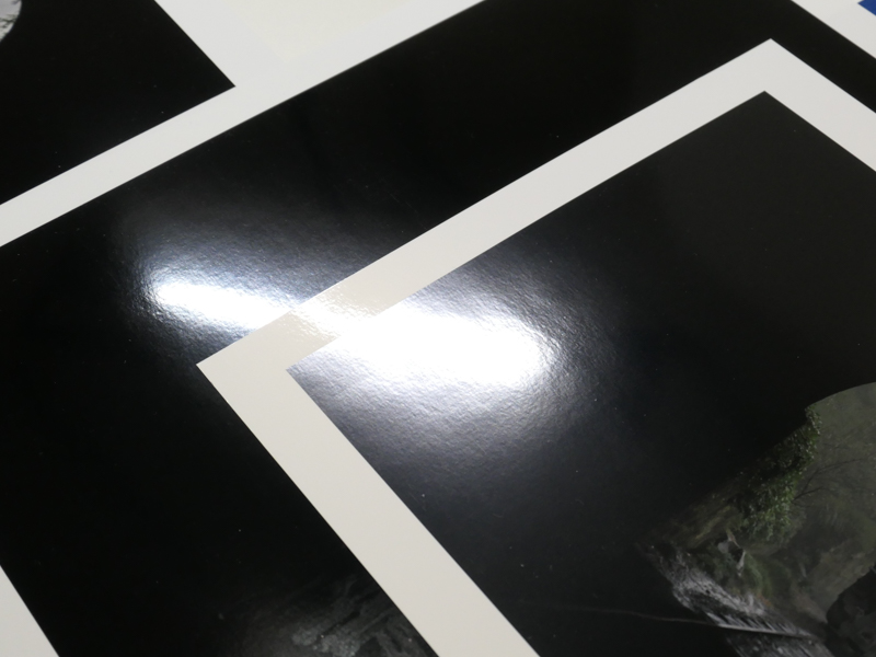 プリントに照明を反射させたところ。左がPX1V、右が従来モデル。乱反射の具合が異なる。