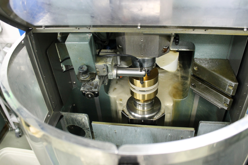 心取り加工機にセットされたレンズ。こうした機械の加工動作が、光学ガラスの加工よりゆっくりしていた。