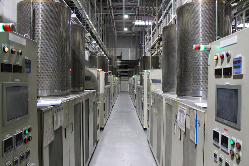 結晶成長装置。2m以上の高さがある。筒状のヒーター部分にルツボがセットされ、ルツボの位置が下降して温度が低下するとともに結晶化が起こる。