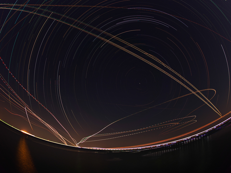 ライブコンポジットを利用して北極星を中心とする星の円周運動と飛行機の光跡を、3時間かけて11,830枚撮影。星空撮影には開放F1.8の明るさが生きる。<br><span class="fnt-85">OM-D E-M1 Mark III / M.ZUIKO DIGITAL ED 8mm F1.8 Fisheye PRO /8mm（16mm相当） / マニュアル露出（F1.8、1秒） / ISO 200 / WB:オート</span>