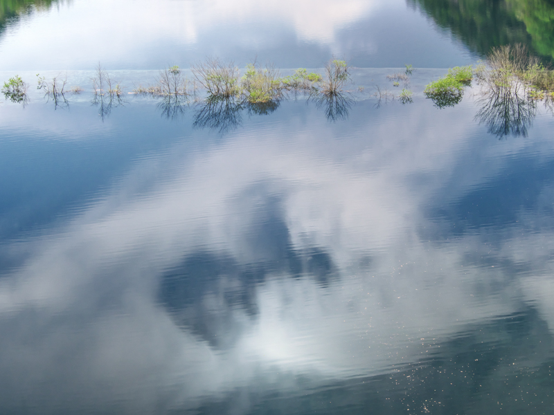 ダムの放流が始まると消えてしまう奥四万湖の浮島。形の良い雲が水面に映り込んでいたため、慌てて手持ちで撮影。軽量のボディ&レンズが何より強い味方となる。<br><span class="fnt-85">OM-D E-M1 Mark II / M.ZUIKO DIGITAL ED 12-40mm F2.8 PRO / 40mm（80mm相当） / 絞り優先AE（F11、1/50秒、-0.7EV） / ISO 200 / WB:オート</span>