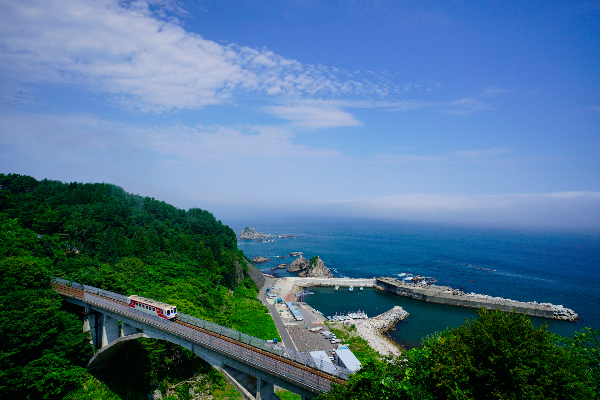 今回ご紹介するのは、東日本大震災で大きな被害を受けながらもみごとに復活した、三陸鉄道リアス線と海をじっくりと撮れる「大沢橋りょう」。三陸鉄道リアス線は、その名のとおりリアス式海岸で有名な三陸海岸に沿って走る路線ですが、意外にも海と絡めて撮影できるポイントは少ないのが実情です。この橋りょうでは海をバックに鉄橋を渡る三陸鉄道の列車を、さまざまな角度から撮影できます。<br>ソニーα7R II FE 16-35mm F4 ZA OSS(21mm) 絞り優先オート(F6.3、1/400秒) ISO 400 WB:太陽光