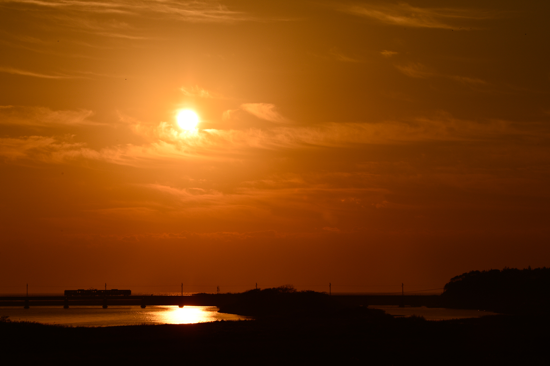 日豊本線・小丸川橋りょうのまわりは広い河川敷。朝のシルエットも並行して架かる国道の橋から撮影するので、ほかの撮影者を気にせず、ゆったりと撮影できます。国道からの撮影で、鉄橋の奥から日が昇るのは9月末から10月初旬。この作品は10月中旬の朝7時少し前に撮影しています。<br>ニコンDf　AF-S NIKKOR 80-400mm f/4.5-5.6G ED VR（130mm）　マニュアル露出（F16、1/2,500秒）　ISO 200　WB:晴天日陰