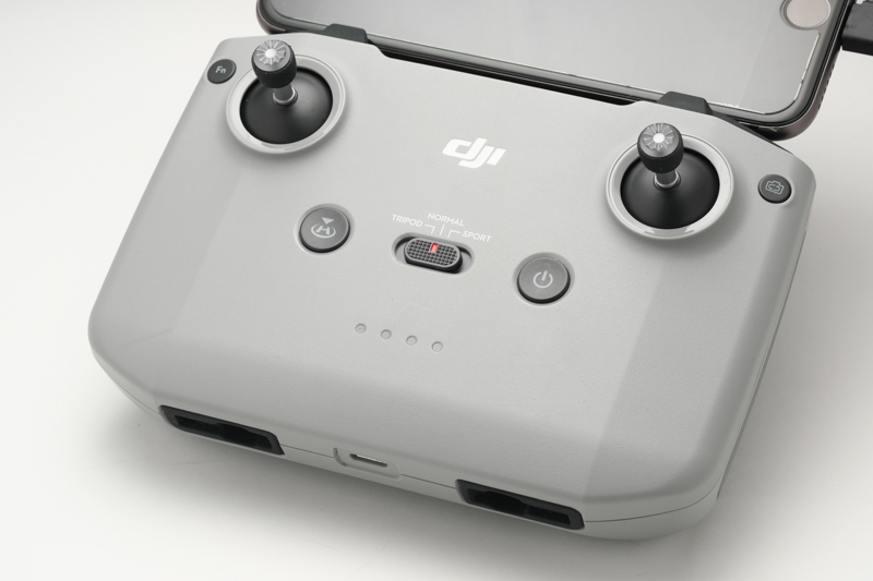 シンプルで分かりやすいボタンレイアウトのプロポ操作面。中央左からRTH（リターン・トゥー・ホーム）ボタン、フライトモード切換スイッチ、電源ボタンと使用頻度の高い操作部材が並ぶ。右上のボタンは静止画/動画モード切換ボタン。