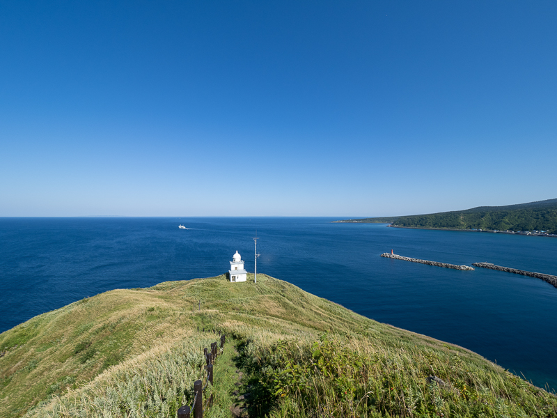 利尻島の玄関口である鴛泊港を出航したフェリーをペシ岬展望台から眺める。<br>E-M1 Mark III　M.ZUIKO DIGITAL ED 7-14mm F2.8 PRO　ISO 200（F8.0・1/500）絞り優先AE　WB晴天