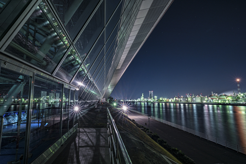 きらびやかな四日市コンビナートの工場夜景と、それが四日市ドームのガラスや水面に映り込む光景が近未来を思わせる。特に広角レンズが生きる構図で、20mm単焦点レンズの描写力が発揮されている<br><span class="fnt-85">Nikon Z 7II / NIKKOR Z 20mm f/1.8 S / 20mm / マニュアル露出（F10、30秒） / ISO 100 / WB:オート</span>