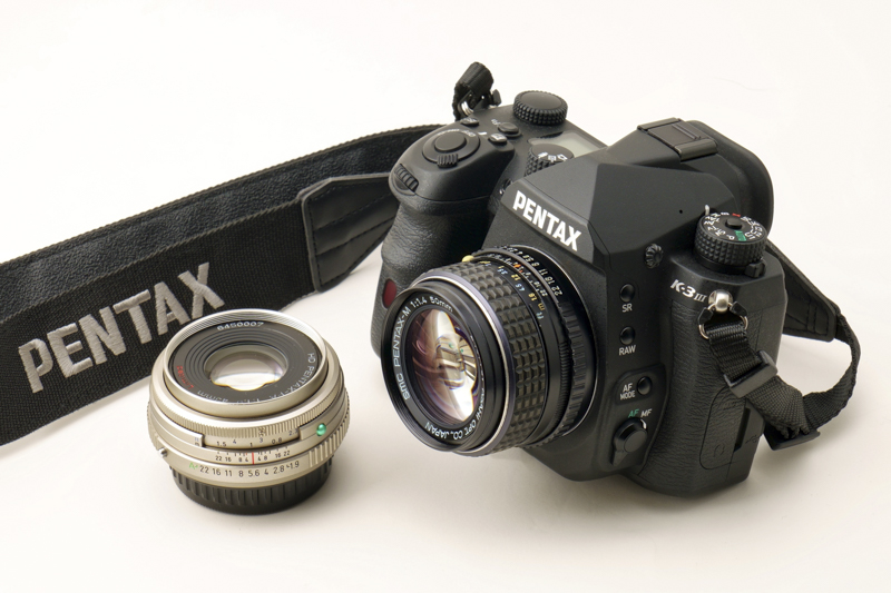大村さんのPENTAX K-3 Mark III。装着レンズはsmc PENTAX-M 50mm F1.4。その横のレンズは4月28日発売予定のHD PENTAX-FA 43mmF1.9 Limited（掲載している作例はリニューアル前のsmc PENTAX-FA 43mmF1.9 Limitedで撮影しています）