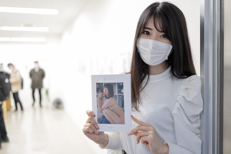 写真展会場入り口にて。販売中の写真集を手に