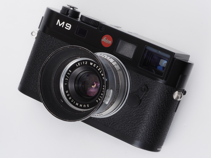 ライカ ズミクロンM F2/35mmの初期モデルのドイツ製ですね。通称1stとか呼びます。後のカナダ製よりよく写り、はるかに良い写真が撮れます。嘘です。<br><br>私の人生の過ちはすべてこの35mmレンズから始まったような気がします。モノクロフィルムだと感動的な描写をしたというのは都市伝説です。早く忘れることです。さらにIROOAフードの奇麗なのを血眼になって探しはじめたりすると、もう手おくれです。このレンズの中古価格を上げたのはアカギだという人がいますが、そんな影響力があったら、いま、ここで原稿は書いていないと思います。