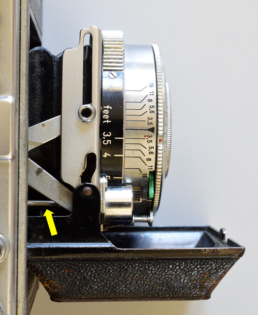 写真1：コダックレチナ1b。蛇腹を用いたフォールディングカメラでセルフコッキングを実現した例。矢印で示したロッドの回転でフィルム巻き上げレバーの動きをシャッターに伝え、チャージしている。