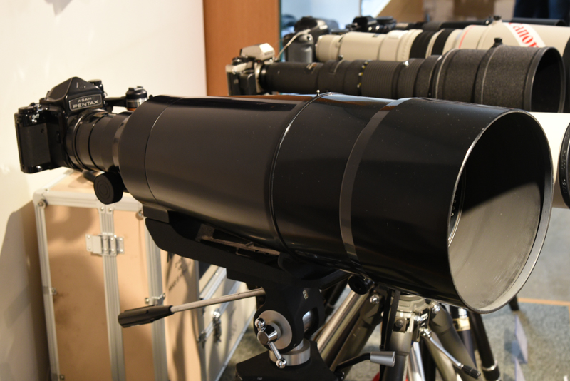 とりわけ大きなレンズは「Super-Multi-Coated TAKUMAR / 6×7 1:4/800」（製造年不詳。旭光学工業：現リコーイメージング）<span class="fnt-85">※6月22日17時修正：製品名に誤りがあったため、日本カメラ博物館に確認のうえ修正しました。</span>