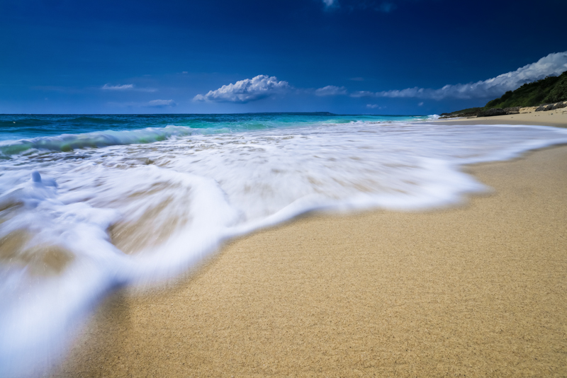 波が這うように迫る様子を、動感を伴って表現した。雲台のすぐ下を波がすり抜けるほど低いポジションを取れて、かつ防水の三脚がこのフレーミングを可能にした。<br><span class="fnt-85">EOS R5 / RF15-35mm F2.8 L IS USM / 17mm / 絞り優先AE（F20、1/10秒、-0.3EV） / ISO 100 / ND+PLフィルター使用</span>