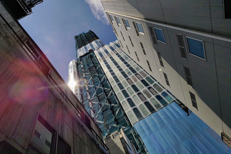 「コンクリートジャングル」って死語ですね。すみませんが、街中を歩いていると、語彙に乏しい私はそのくらいの言葉しか浮かびません。建築中の建物に向かい、けっこう強めの太陽のリフレクションを入れたら、お待ちかねのゴーストが出ました。<br>Leitz Phone 1（F1.9・1/12,800秒）ISO 53