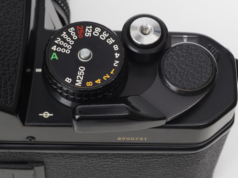 ニコンFE2のボディ上部。シャッターダイヤル表記は250表示が赤。別にM250とありますが、メカシャッターの意味ですね。「B」もメカシャッターです。電池がなくても動くということはこの当時のニコン一眼レフでは必須の仕様。A位置は緑ですが、ニコンDfやZ fcでは「1/3STEP」表記が緑色です。これはデザイン的に絞り優先AE機のダイヤルに似せてきている感じがします。
