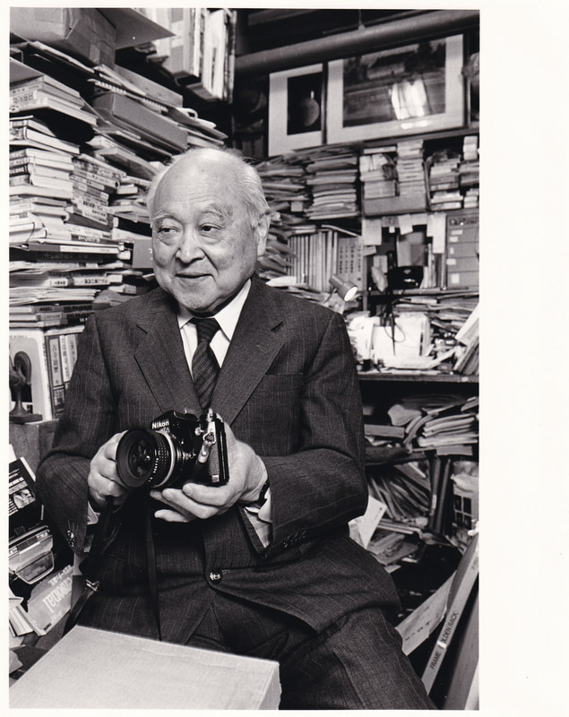 FM/FEを使用している写真家の写真がないかと探してみたら、巨匠 渡辺義雄先生（1907-2000）の写真が出てきました。撮影は1990年くらいで場所は四ツ谷の事務所ですね。この写真を撮影したカメラはニコンFE2でした。渡辺先生は戦後建築写真の第一人者ですが、戦前は小型カメラでスナップも撮影されていました。手にしたカメラはFE2でしょうか。「最近は小さいカメラがいい」とお話をされていたことは記憶に残ります。ついているレンズはAi Nikkor 20mm f/2.8Sです。のちに渡辺先生にこのプリントを差し上げたら「焼きが悪い」と叱られたこと思い出しました。お詫びします。<br>ニコンFE2　Ai Nikkor 35mm f/1.4S（F4・1/60秒）Kodak T-MAX400