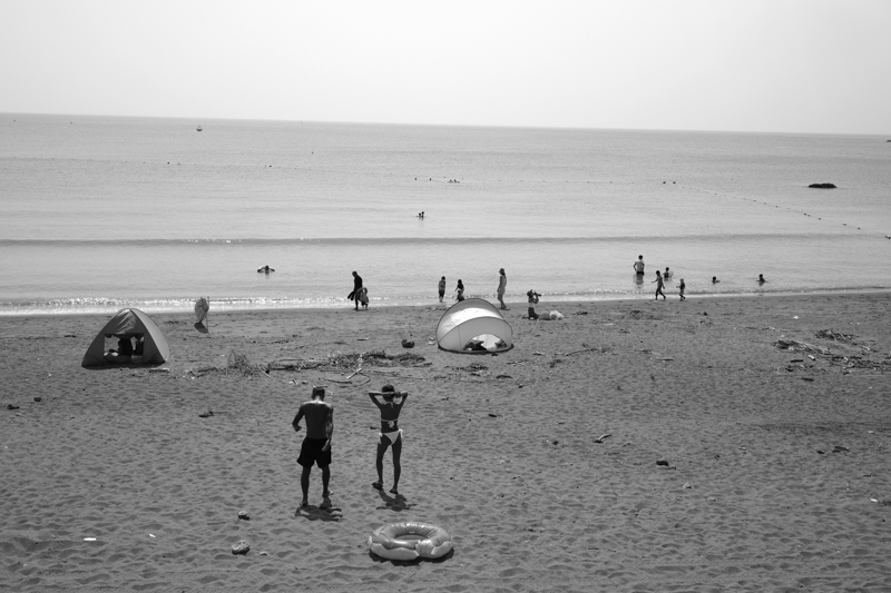 湘南の浜辺で日焼けをしながら、くつろいでいたカップル。立ち上がると海に向かって歩き出した。とっさにカメラを構えてシャッターを切る。このレスポンスこそがGRの魅力だ<br><span class="fnt-85">RICOH GR IIIx／40mm／プログラムAE（F5.6、1/1,250秒、±0.0EV）／ISO 125／オートWB／モノトーン</span>