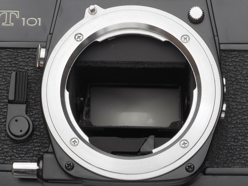 SR-T101のマウント部。「ミノルタSRマウント」と呼ばれたり、「ミノルタバヨネットマウント」という呼び方もされます。マウントアダプターの表記では「MD」と書いてあるものが多いのですが、これはミノルタXD以降の両優先対応のMDロッコールレンズ登場後につけられた愛称ですね。11時方向にあるのがMCロッコールの爪とカップリングするレバー、1時方向にあるのはレンズ取り外しボタン。7時方向にあるのはプレビューボタンです。