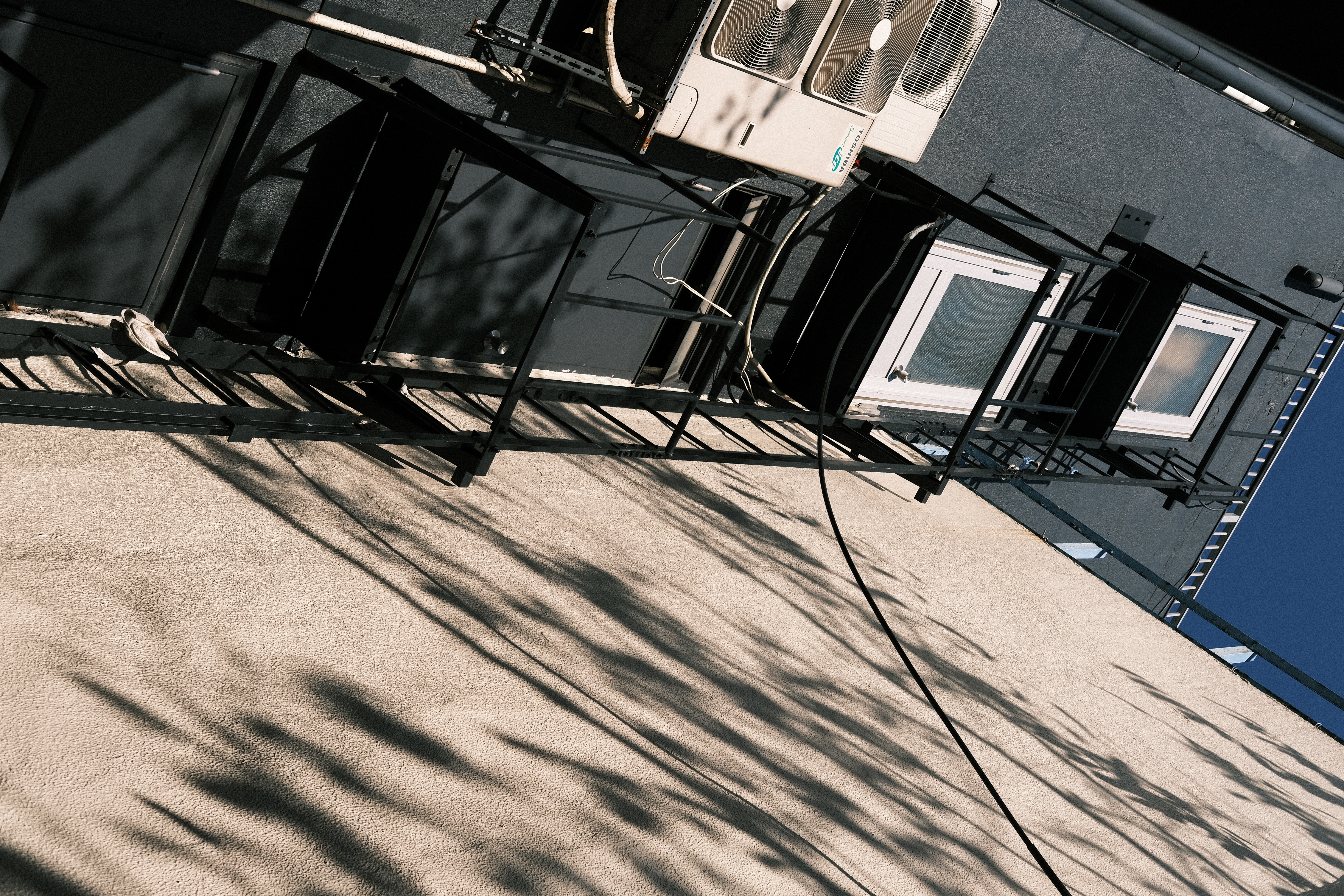 建物に強い光が当たり、壁に映る樹木の影に惹かれた。クラシックネガは彩度が低めで独特の色調だ。青空は入っているが、カラークローム・ブルーはオフの状態。<br>X-E4　XF35mm F2 R WR（絞りF8）ISO 160