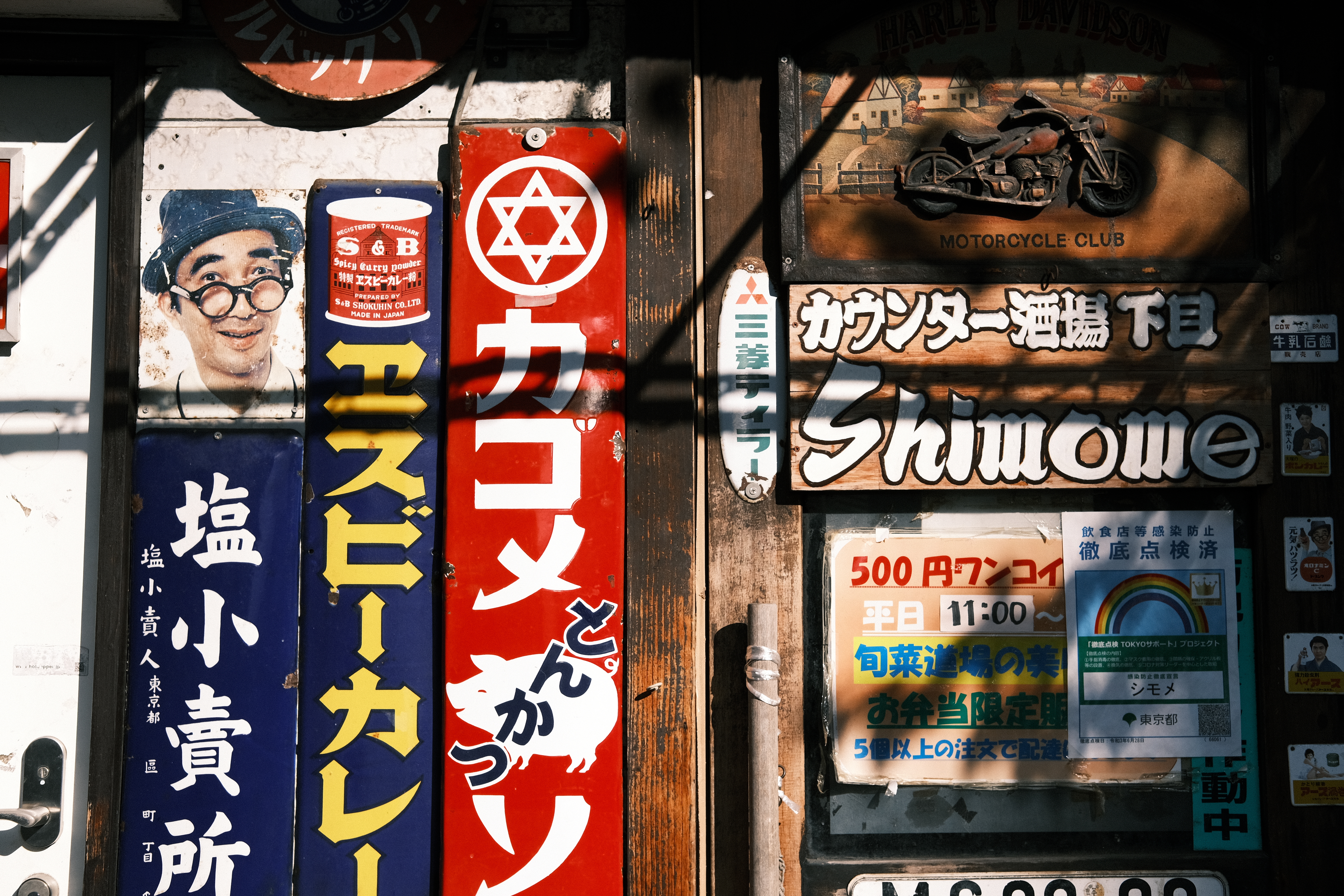 懐かしい昭和の広告が貼られた壁。彩度は低くても地味にはならない。またカラーを＋1にしているため、色のメリハリもある。トーンカーブでデフォルトよりわずかにコントラストを上げたおかげでインパクトのある仕上がりになった。<br>X-E4　XF35mm F2 R WR（絞りF5.6）ISO 160