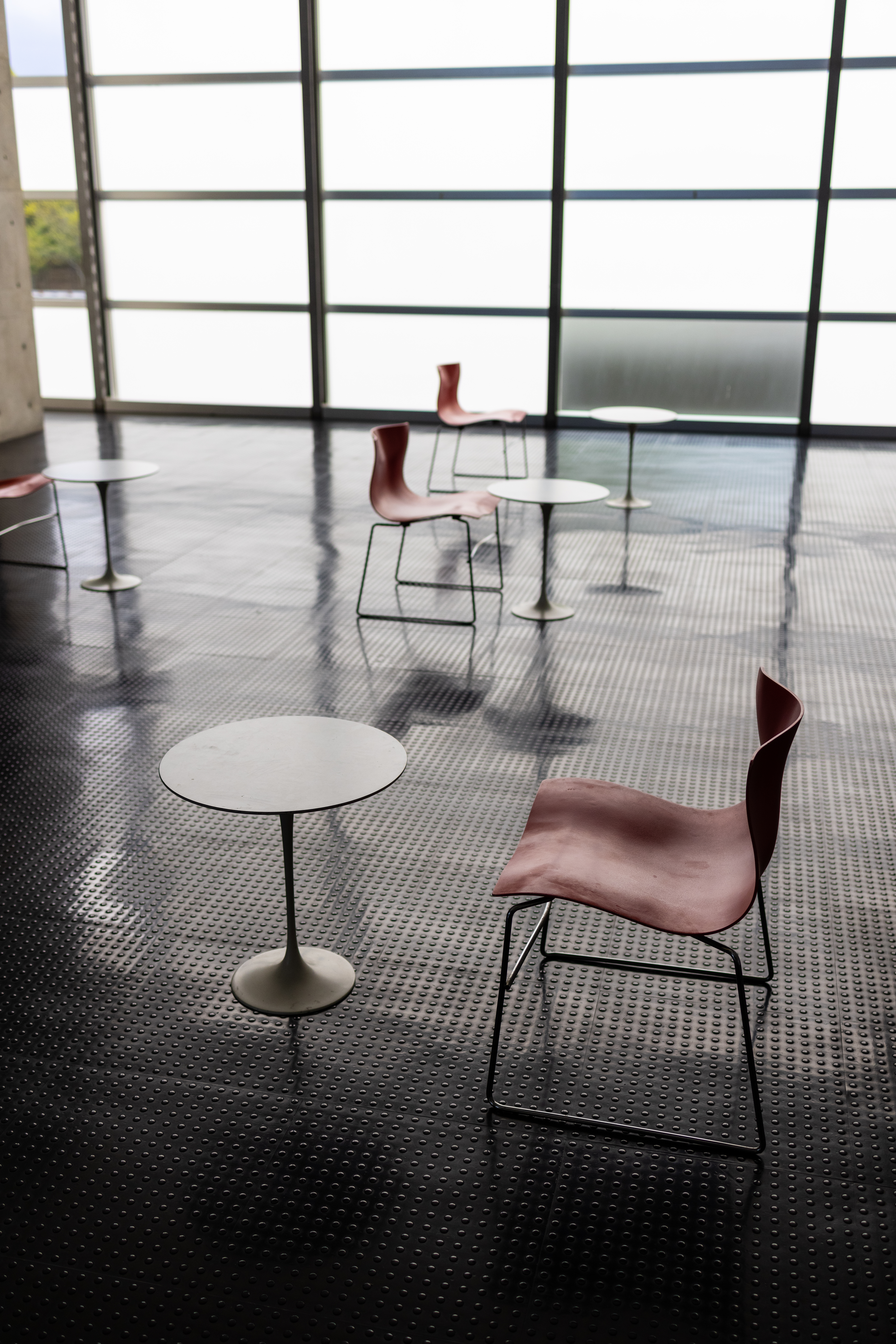 コロナ前はたくさんのテーブルと椅子が並んでいた休憩所だが、ひとつのテーブルに椅子は1脚だけになった。壁面全体の大きなガラス窓がら日が差し込む空間。<br>EOS R5 / RF35mm F1.8 MACRO IS STM / 絞り優先AE（F2.8・1/750秒・±0EV） / ISO 400