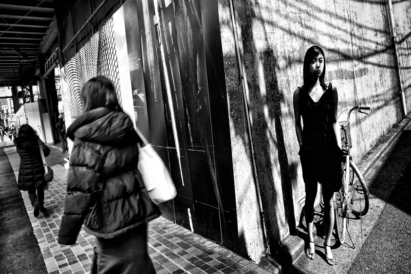 西武新宿駅前通りの建築中ビルの外壁に森山大道の作品がプリントされている。宇多田ヒカルさんを写した作品と街を行き交う人を重ねる<br><span class="fnt-85">RICOH GR III／28mm相当／プログラムAE（F2.8、1/30秒、±0EV）／ISO 200／WB：オート</span>