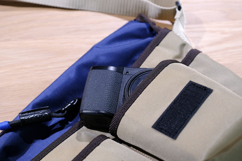 Loopie Wポケットショルダー。リサイクルナイロン素材「CODURA ECO」が用いられており、重量は約200g。220×170×100mmというサイズ感からは想像できないほどの軽さが特徴だ。フロントにはポケットを2つ備えており、RICOH GRシリーズやスマートフォンなどを収納することができる。