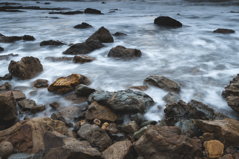 岩の質感や波が描く白い筋が浮かび上がり立体的に見える
