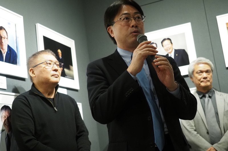 Vol.11のオープニングパーティーで挨拶する現OMデジタルソリューションズの杉本繁実社長。左は写真家の加納典明さんと、右は同じく写真家の湊和雄さん